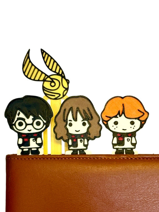Three cartoon characters with a golden snitch on a brown surface